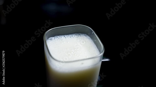 Close-up of a glass filled with milk on a dark background, showing a creamy top and soft light, Glass of milk on dark background