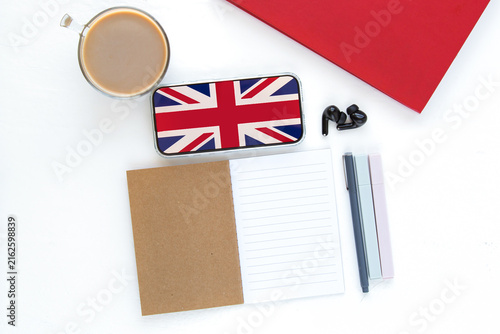 Foto Workspace with notebook, smartphone displaying UK flag, cup of coffee, earphones