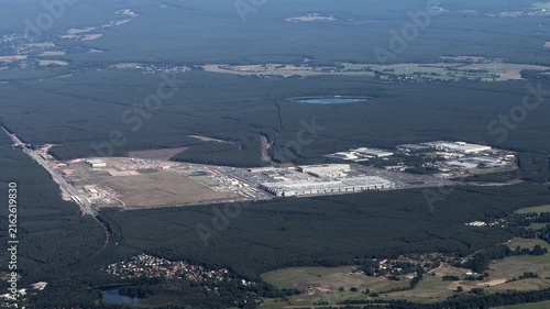 flying along Tesla Gigafactory 4, a manufacturing plant for Tesla Inc located southeast of central Berlin, in Brandenburg, GER, surrounded by forest and countryside landscape - 4k aerial video footage