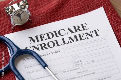 Close-up of a medicare enrollment form  stethoscope  and alarm clock on red textured surface