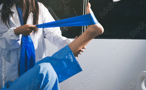 Doctor checks Asian senior woman patient after knee replacement operation in hospital room. Nurse examines leg after surgery. Medicine health treatment therapy healthcare concept