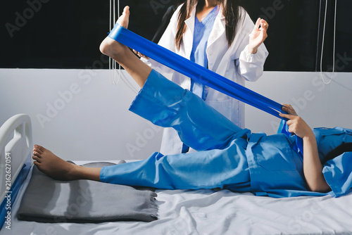 Doctor checks Asian senior woman patient after knee replacement operation in hospital room. Nurse examines leg after surgery. Medicine health treatment therapy healthcare concept