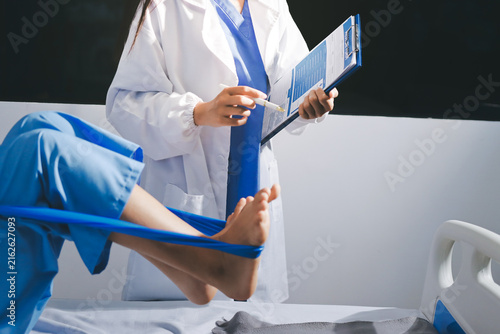 Doctor checks Asian senior woman patient after knee replacement operation in hospital room. Nurse examines leg after surgery. Medicine health treatment therapy healthcare concept