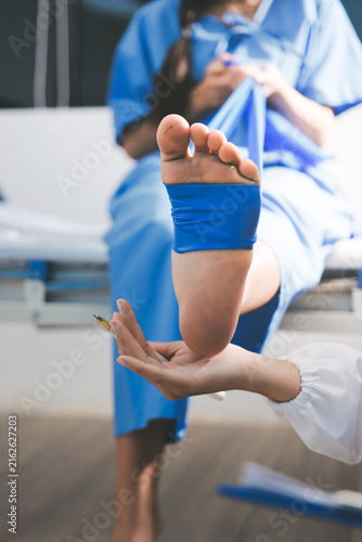 Doctor checks Asian senior woman patient after knee replacement operation in hospital room. Nurse examines leg after surgery. Medicine health treatment therapy healthcare concept