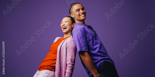 Smiling friends stand back to back in a vibrant studio setting