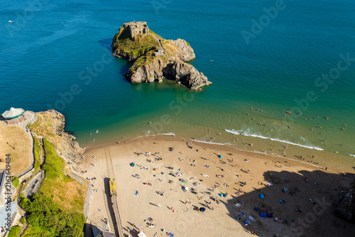 Bild auf Leinwand Sandy cove beach busy with holidaymakers next to rocky tidal island fort, calm t