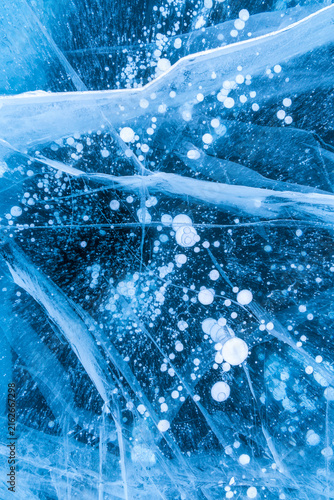 Abstract winter landscape of vibrant blue ice, cracked lines, and captured methane bubbles. Lake Baikal, Russia.