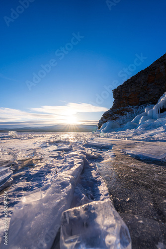 Fotografía Sunburst over frozen Lake Baikal's hummocks and cliffs.