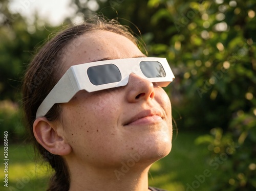 Young woman wearing protective eclipse glasses to watch a solar eclipse