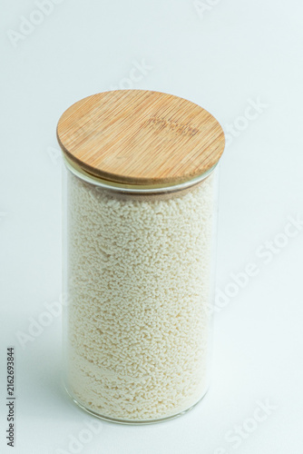 Glass jar with wooden lid filled with mushroom bouillon powder seasoning isolated on white background