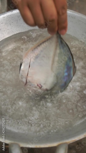 Cooking Asian-style steamed fish (Pla Neung Si Ew) by blanching and steaming whole fish, then pouring hot seasoned soy sauce over ginger, chilies, and scallions.