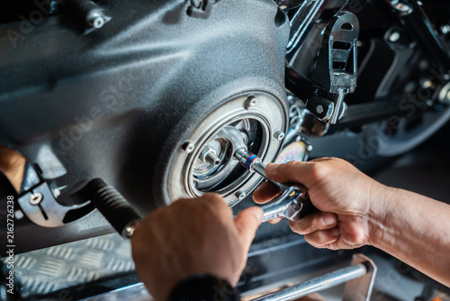 Mechanic hands using ratchet socket wrench to tighten bolts on motorcycle primary engine clutch cover