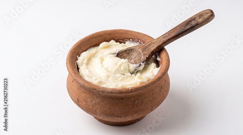 Fresh homemade white butter in a rustic terracotta pot with a wooden spoon, traditional Indian dairy product, creamy healthy clarified butter for cooking and baking.