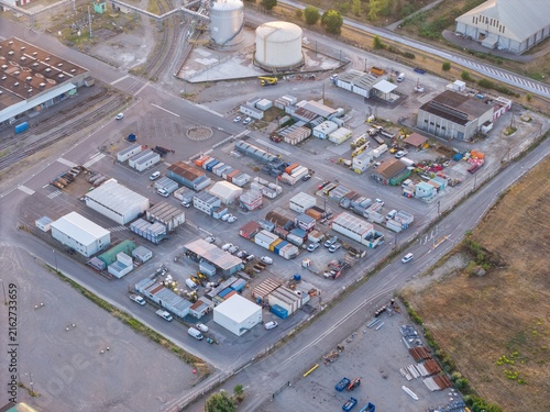 Aerial view of an industrial logistics site featuring numerous shipping containers, temporary office structures, storage tanks, and parked vehicles in Bantzenheim, Grand Est, France.