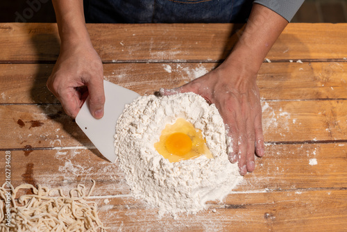 Canvas Print Hands mixing flour and egg on a wooden table while making fresh pasta dough