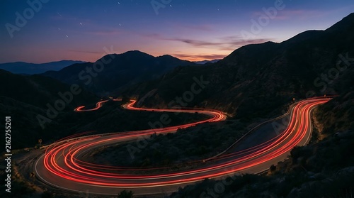 Winding mountain road with long exposure car light trails at sunset in the evening
