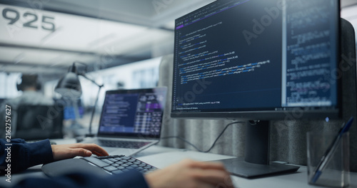 Fotografie Unrecognizable Software Developer Typing Program Code and Sql Database Queries on a Desktop Computer Display and Laptop, Building a Cloud Application in an Office With a Diverse Team of Programmers