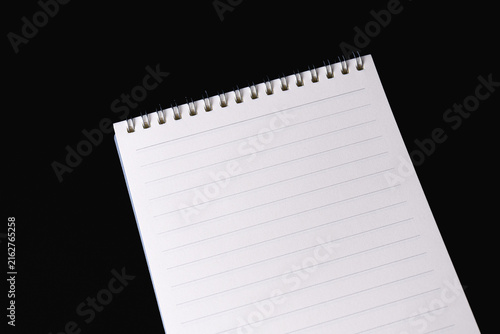 Blank open spiral notebook resting on a dark black background