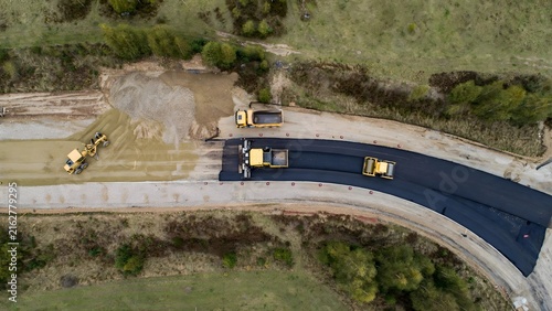 Aerial view of road construction site with heavy machinery paving new asphalt highway.