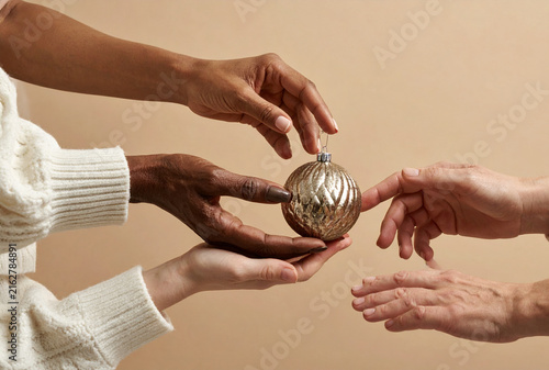 Diverse Hands of All Ages Reaching for a Christmas Bauble