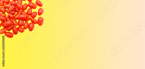 Piccoli pomodori maturi dalla forma allungata ammucchiati su uno sfondo di colore giallo con spazio per testo