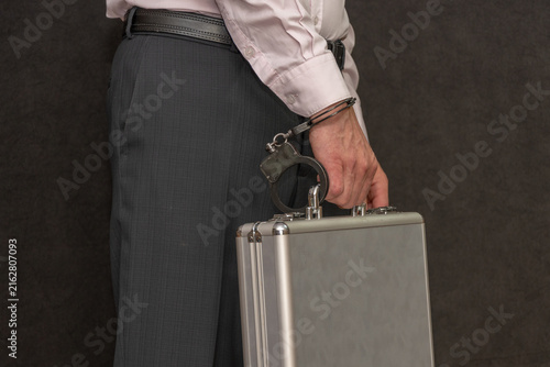 Obraz na plátně Businessman with handcuffs holding metal briefcase beside trouser pocket in stud
