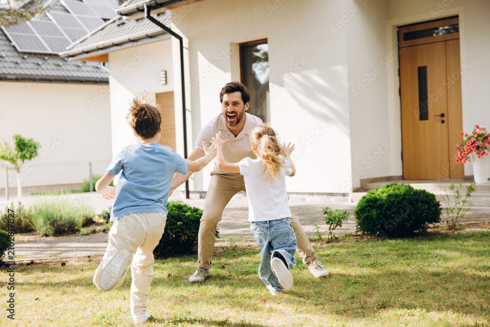 Obraz premium Happy father playing with children in garden at home