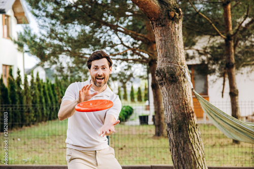 Obraz na płótnie Man playing frisbee in backyard enjoying leisure time