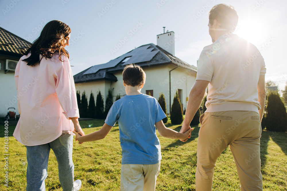 Fototapeta premium Family walking holding hands towards solar panel house