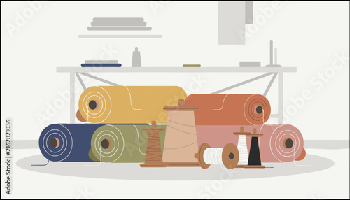 Assorted colorful fabric rolls and various wooden sewing spools with threads displayed neatly within a professional tailoring workshop environment.