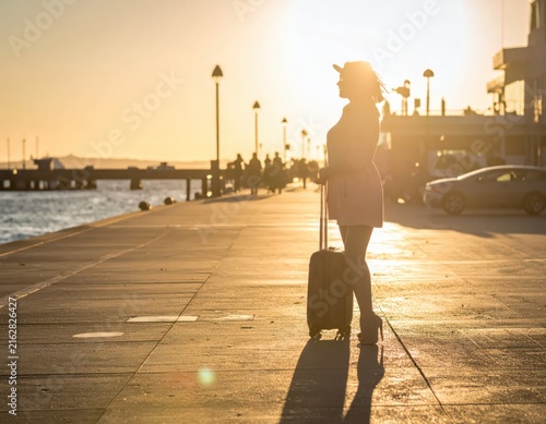 Woman Silhouette Against Sunset at Waterfront with Luggage on a Scenic Pier Journey