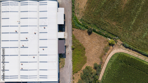 Aerial view of a cold finished steel manufacturing facility with a large metal roof and adjacent agricultural fields in Milan, Lombardy, Italy.