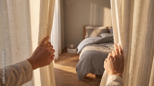Close Up Hands Opening Elegant Curtains in a Contemporary Bedroom