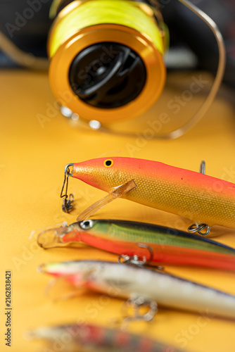 Cuadro en lienzo Golden fishing reel spool and plastic wobbler lure on yellow backdrop The Concep