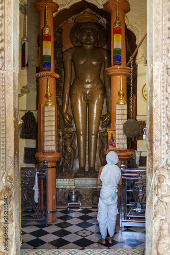 India. Madhya Pradesh. Khajuraho. A worshipper in white ceremonial robes prays before the monumental statue of a Tirthankara at the Shantinath Temple