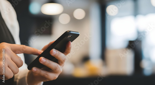 Professional holding a smartphone device to interact with digital mobile applications and connect via wireless network technology in a modern office