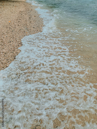 Konstfotografi Foamy Ocean Waves Washing Over a Seashell Covered Beach