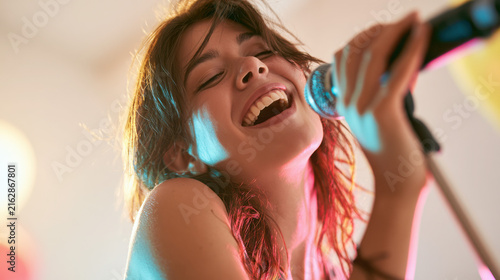 Young woman singing passionately into a microphone at a party  
