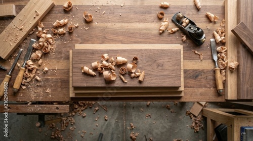 Workbench showing carpentry tools like chisels and a hand plane alongside wood boards and curly shavings, representing craft