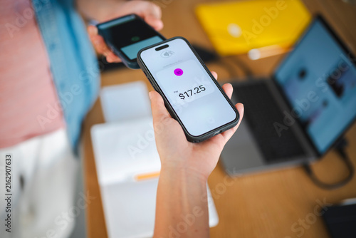 A person makes a contactless mobile payment by holding their smartphone over another device. This efficient digital transaction takes place in a modern office.