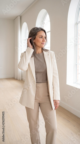 Professional businesswoman wearing elegant cream blazer in bright office