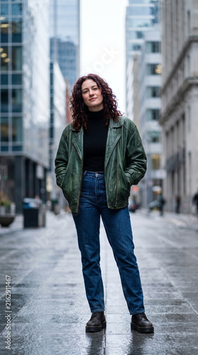 Confident woman in green leather jacket standing on urban city street