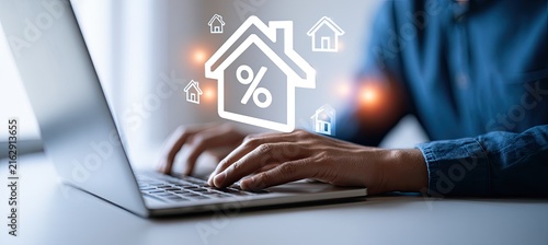 Person using laptop with digital overlay of house and percentage symbol, representing real estate and finance concepts.