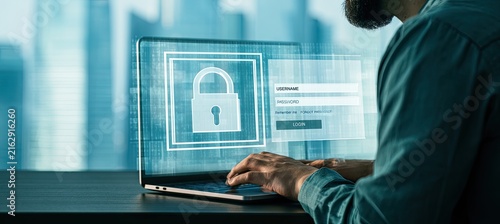 Cybersecurity concept - Person using laptop with glowing digital padlock icon on screen.