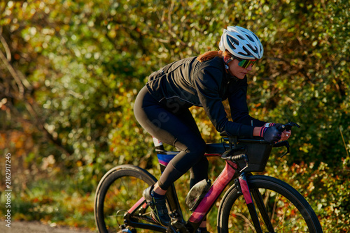 Female Cyclist Training on Road Bike in Autumn Countryside Wearing Helmet and Sunglasses