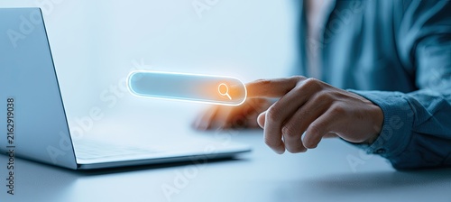 Person using a laptop and interacting with a digital search bar interface.