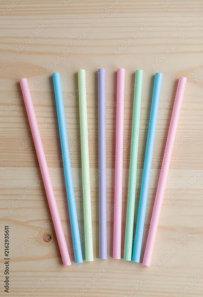 Fototapeta premium Plastic straw waste and environmental impact, colorful drinking straws on a wooden background, single-use plastic pollution