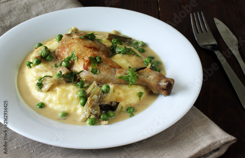 Creamy chicken leg meal served on mashed potatoes with green peas and herbs