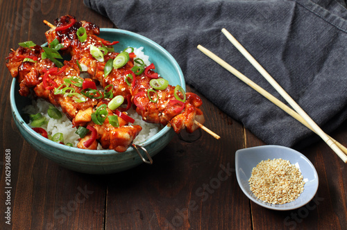 Korean style glazed chicken skewers served over white rice with green onion, chili, and sesame seeds