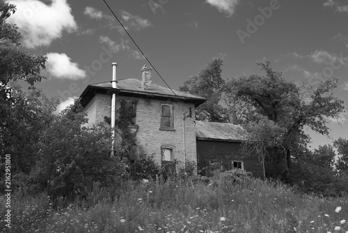 Black and white image of an Abandoned boarded up farm house 